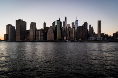 New York 'ta günbatımında, Hudson nehrinin karşısından New York' taki Brooklyn Köprüsü Parkı 'ndan çekilen güzel Manhattan siluetinin manzarası.