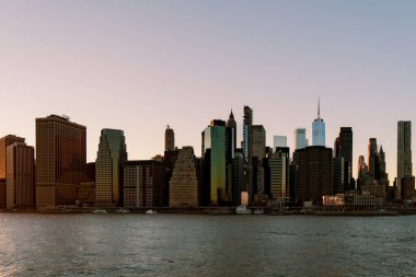 New York 'ta günbatımında, Hudson nehrinin karşısından New York' taki Brooklyn Köprüsü Parkı 'ndan çekilen güzel Manhattan siluetinin manzarası.