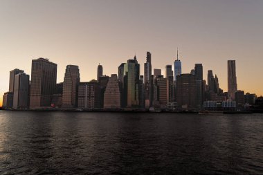 New York 'ta günbatımında, Hudson nehrinin karşısından New York' taki Brooklyn Köprüsü Parkı 'ndan çekilen güzel Manhattan siluetinin manzarası.