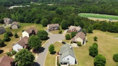 ABD 'nin banliyölerinde arka planda park manzaralı güzel evleri olan lüks bir banliyöde uçarken çekilmiş 4K hava videosu.