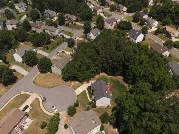 Panoramic aerial view of a suburb with beautiful houses and manicured lawns shot during a sunny day in summer of 2022