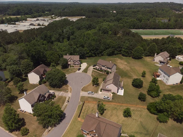 Panoramic aerial view of a suburb with beautiful houses and manicured lawns shot during a sunny day in summer of 2022