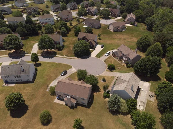Panoramic aerial view of a suburb with beautiful houses and manicured lawns shot during a sunny day in summer of 2022