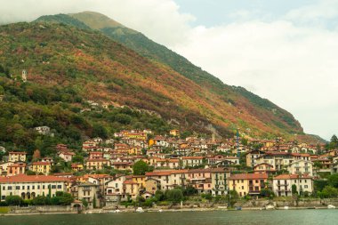 İtalya 'daki Como Gölü' nün renkli evlerle benekli dağlarla çevrili ve 2022 sonbaharında renk değiştiren ağaçlarla kaplı güzel manzarası.