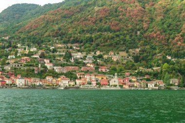 İtalya 'daki Como Gölü' nün renkli evlerle benekli dağlarla çevrili ve 2022 sonbaharında renk değiştiren ağaçlarla kaplı güzel manzarası.
