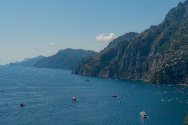 Ünlü Amalfi kıyı şeridinin panoramik manzarası ve turist taşıyan teknelerle dolu dağ.