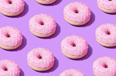 Mor bir arka planda pembe donut deseni. Modayı takip eden yaz estetiği. Canlı renkler. Tatlı yiyecek görsel konsepti.