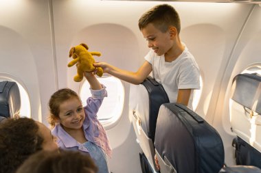 Pencere kenarındaki uçakta oynayan sevimli çocuklar.