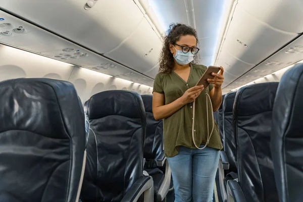 Dospělá žena se dívá na obrazovku telefonu v letadle — Stock fotografie