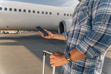 Uçuştan önce elinde akıllı telefon ve tarak tutan bir erkek yolcu.