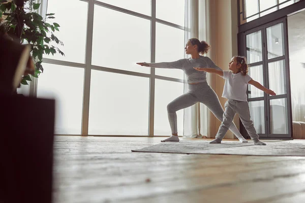 Glückliches kleines Mädchen beim Yoga mit Mama zu Hause — Stockfoto