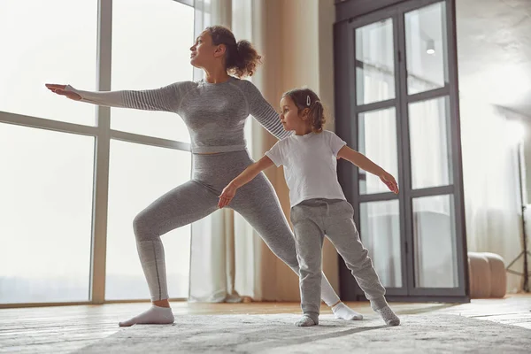 Ruhige Frau beim Yoga mit Tochter zu Hause — Stockfoto