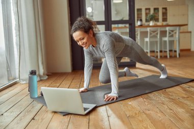Gülümseyen kadın bilgisayarla çevrimiçi eğitim yapıyor.