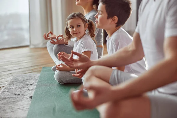 Glückliches kleines Mädchen praktiziert Meditation mit der Familie — Stockfoto