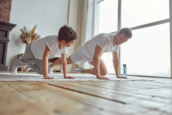 Niño haciendo tablón con papá en el interior —  Fotos de Stock