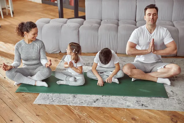 Fröhliche Eltern bringen Kindern Meditation zu Hause bei — Stockfoto