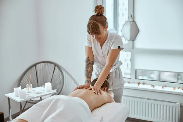 Professionell säker massage mästare gör procedurer för att kaukasiska kvinna i minimalistiska moderna skåp — Stockfoto