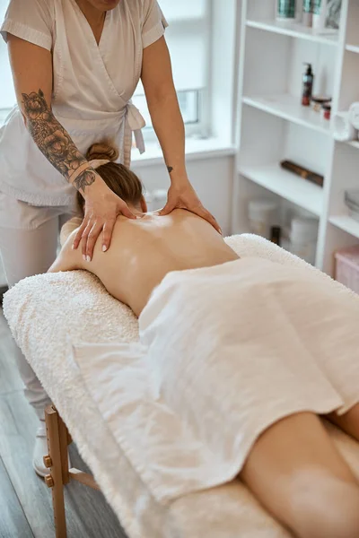 Maître professionnel de massage confiant fait des procédures à la femme caucasienne dans le cabinet moderne minimaliste — Photo