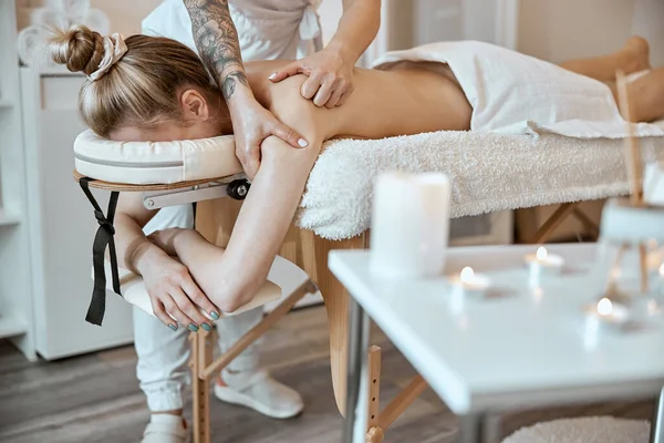 Professionele zelfverzekerde massage meester doet procedures om Kaukasische vrouw in minimalistische moderne kabinet — Stockfoto