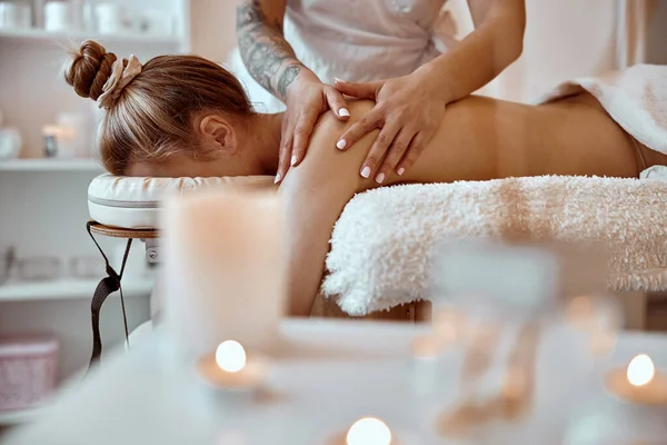 Profesjonell selvtillit massasjemester utfører prosedyrer for kvinner i minimalistiske moderne kabinett – stockfoto