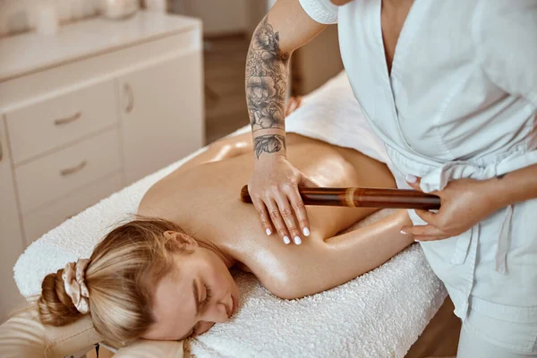 Professionele zelfverzekerde massage meester doet procedures om Kaukasische vrouw in minimalistische moderne kabinet — Stockfoto
