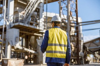 Defterli erkek mühendis fabrikada çalışıyor.