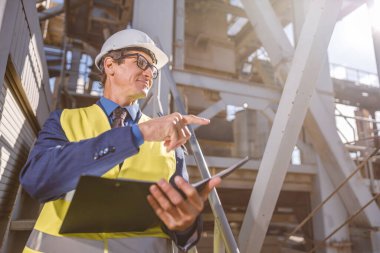Elinde fabrikayı gösteren belgeler olan erkek mühendis.