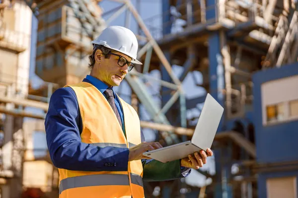 Man ingenieur werken op laptop buiten in de fabriek — Stockfoto