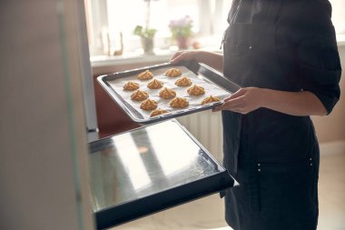 Kendine güvenen profesyonel bir kadın, evdeki hafif modern mutfakta kremalı pasta hazırlıyor.