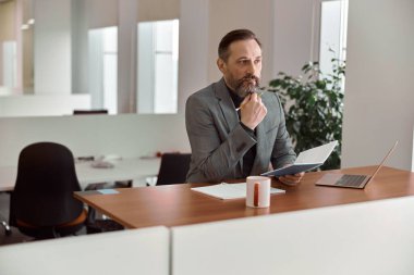 Mutlu yetişkin beyaz adam modern bir ofiste çalışıyor.