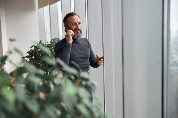 幸せなスマート大人の原因アジアのビジネスマンはオフィススペースの大きな窓の近くに立っているとスマートポーズを保持 — ストック写真
