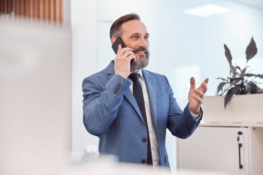 Kafkasyalı mutlu iş adamı modern şık bir ofiste akıllı adam kullanıyor.