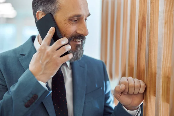 現代的なスタイリッシュなオフィスでスマートフォンを使用して幸せな大人の白人ビジネスマン — ストック写真