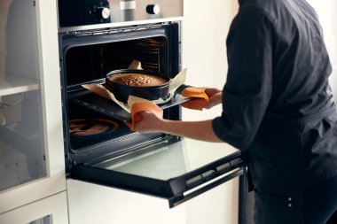 Genç profesyonel kadın aşçı, açık modern mutfağında lezzetli bir pasta hazırlıyor.