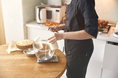 Genç profesyonel kadın aşçı, açık modern mutfağında lezzetli bir pasta hazırlıyor.