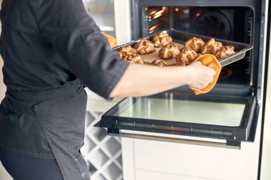 Kendine güvenen profesyonel bir kadın, evdeki hafif modern mutfakta kremalı pasta hazırlıyor.