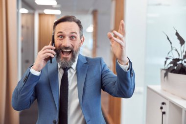 Kafkasyalı mutlu iş adamı modern şık bir ofiste akıllı adam kullanıyor.