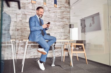 Mutlu yetişkin beyaz adam modern bir ofiste çalışıyor.