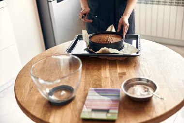 Genç profesyonel kadın aşçı, açık modern mutfağında lezzetli bir pasta hazırlıyor.