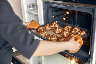 Kendine güvenen profesyonel bir kadın, evdeki hafif modern mutfakta kremalı pasta hazırlıyor.