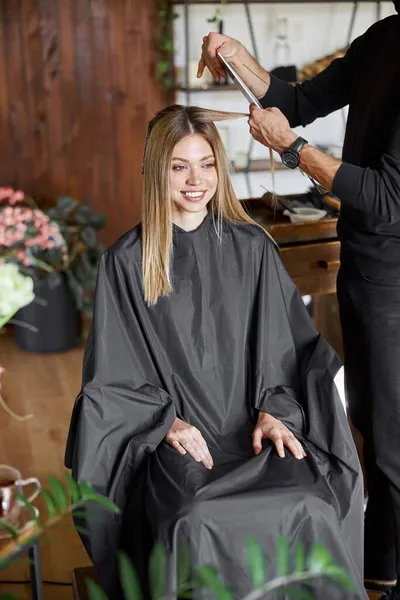 Ο σίγουρος άντρας στυλίστας βάφει τα μαλλιά μιας ξανθιάς καυκάσιας πελάτισσας. — Φωτογραφία Αρχείου
