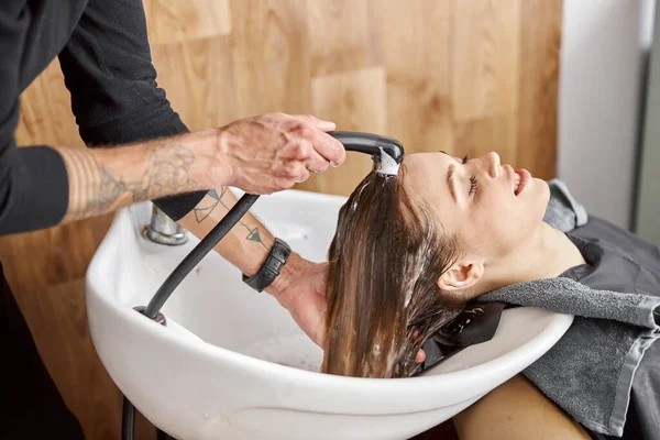 Estilista de confianza es el lavado de cabello de un hermoso cliente femenino caucásico en el salón —  Fotos de Stock