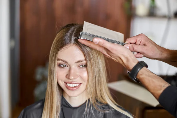 Estilista masculino seguro es teñir el cabello de rubia caucásica cliente femenino —  Fotos de Stock