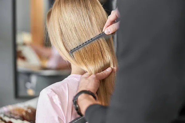 Pofessionell frisör kammar ett hår av vackra kaukasiska blond kvinna i modern salong — Stockfoto