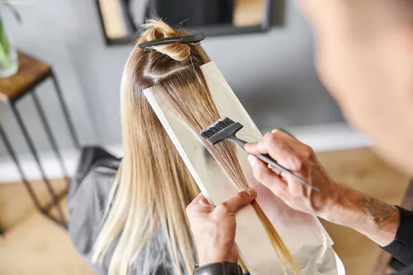 Zelfverzekerde mannelijke stylist is het verven van haar van blonde Kaukasische vrouwelijke client — Stockfoto