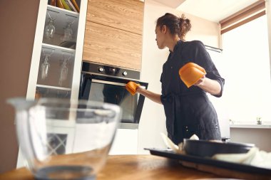 Genç profesyonel kadın aşçı, açık modern mutfağında lezzetli bir pasta hazırlıyor.