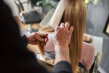 Pofessional kuaför modern kuaförde beyaz saçlı güzel bir kadının saçını tarıyor.