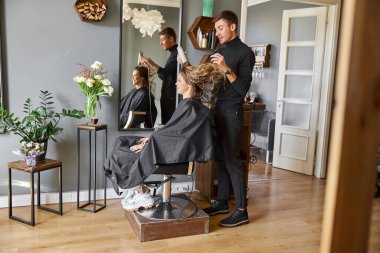 Güzeller güzeli beyaz saçlı güzel kadın güzellik salonunda. Erkek efendi saçlarını kurutuyor.