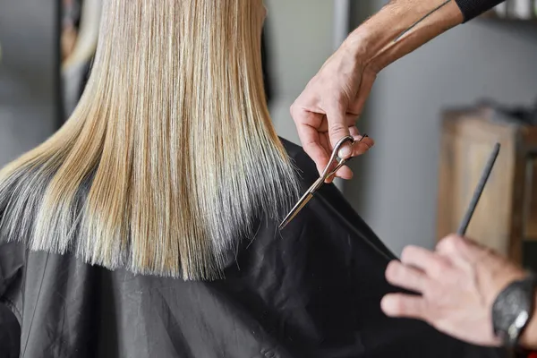 Cabeleireiro está cortando cabelo de mulher loira é salão — Fotografia de Stock
