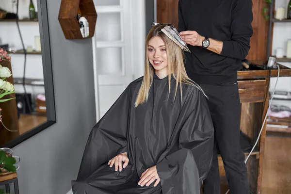 Självsäker manlig stylist färgar håret av blond kaukasisk kvinnlig klient — Stockfoto